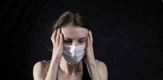 woman in black tank top covering her face with her hands