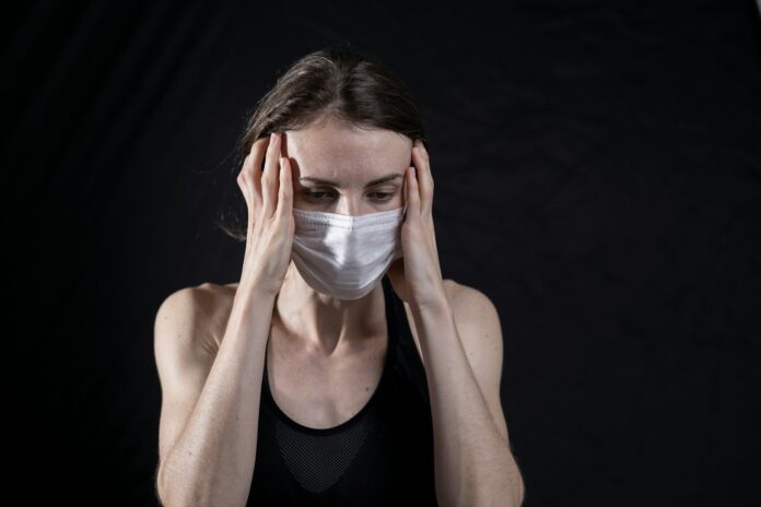 woman in black tank top covering her face with her hands
