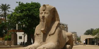 A statue of a seated sphinx in a courtyard