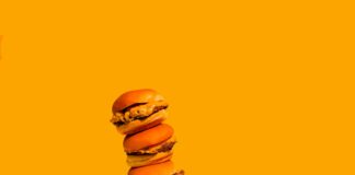 a stack of hamburgers and french fries on a yellow background
