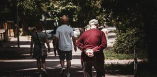 man in red hoodie walking on sidewalk during daytime
