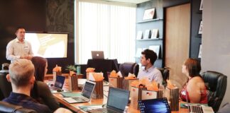 man standing in front of people sitting beside table with laptop computers
