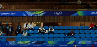 Curling match with athletes sliding stones on ice.