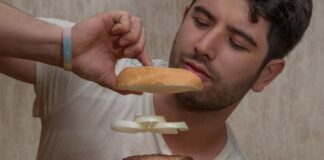 man in white crew neck t-shirt holding burger