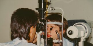 Optometrist examining a patient's eye with equipment.