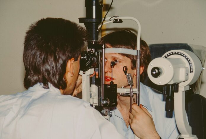 Optometrist examining a patient's eye with equipment.