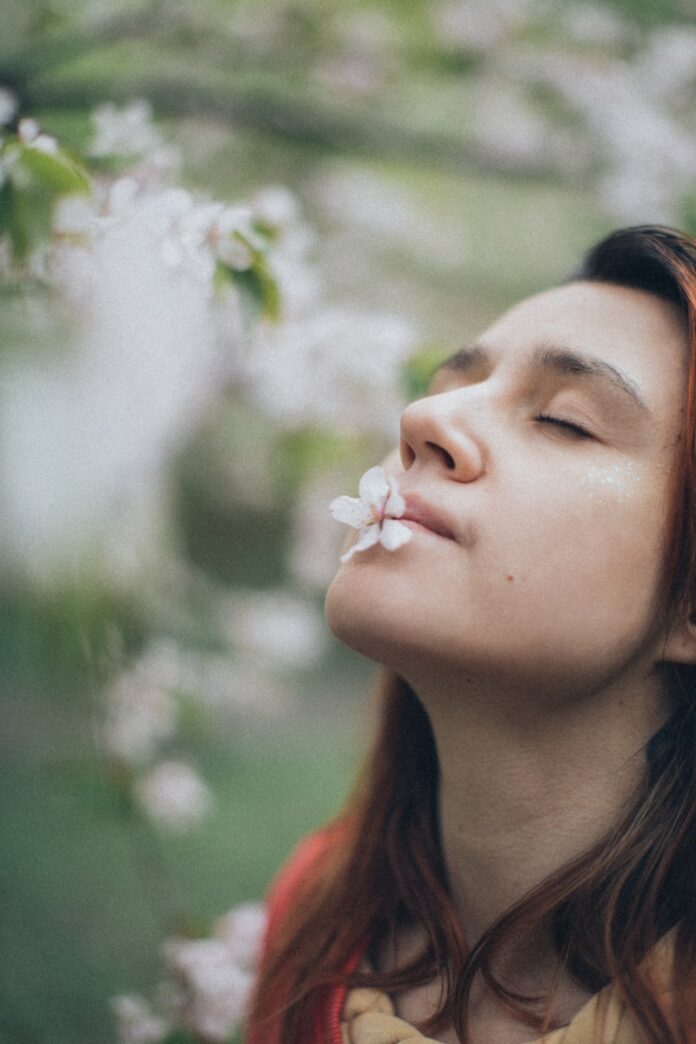 a woman with her eyes closed and a flower in her mouth