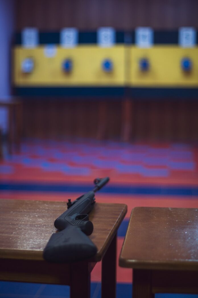 Rifle resting on a wooden table in a shooting range.
