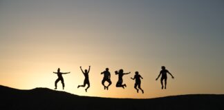 six silhouette of people jumping during sunrise
