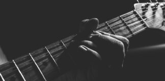grayscale photo of person holding guitar neck and strings
