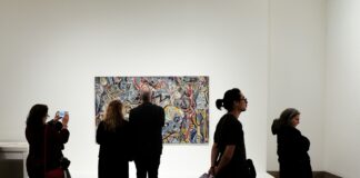 a group of people standing in front of a painting