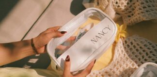 Hands holding a clear cosmetic bag with nancy label