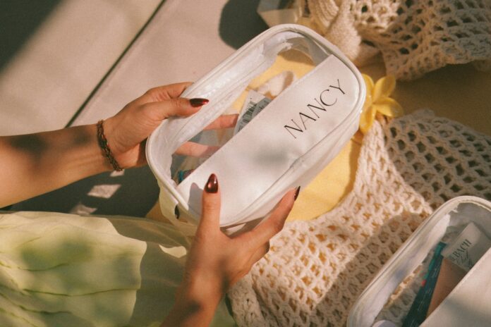 Hands holding a clear cosmetic bag with nancy label
