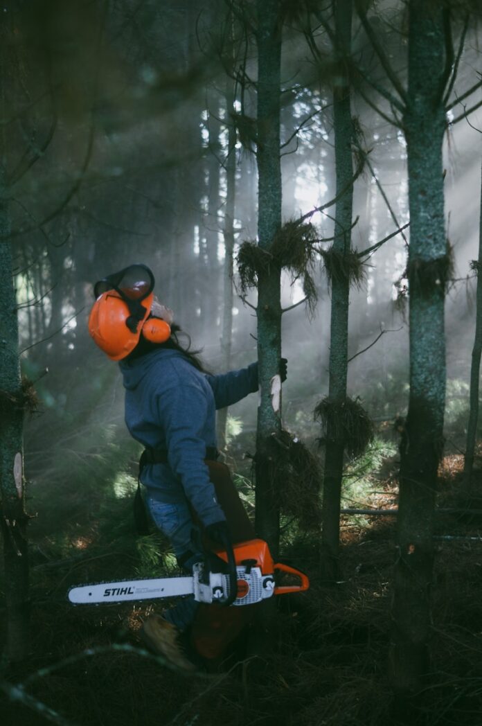 a person in a helmet holding a snowboard in the woods