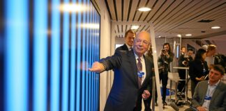 man in black suit pointing in blue screen on wall