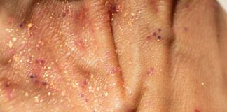 Close-up of a hand with glitter and makeup.