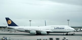 white and black Lufthansa airliner near vehicles