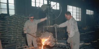 two men in a factory working on a piece of metal