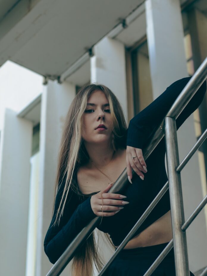 a woman with long hair standing on a stair case