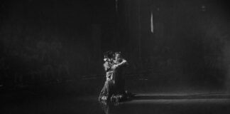 A couple dances gracefully in the spotlight.