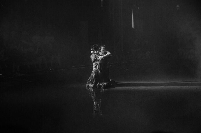 A couple dances gracefully in the spotlight.