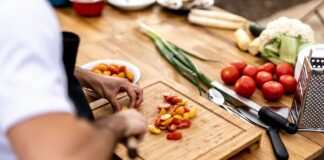 a person cutting up vegetables on a cutting board