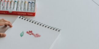 person dipping paintbrush on paint