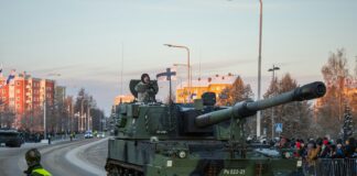 a tank driving down a street next to a crowd of people