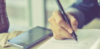 a person writing on a piece of paper with a pen