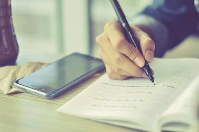 a person writing on a piece of paper with a pen