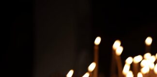 A hand lighting a candle in a dark room.