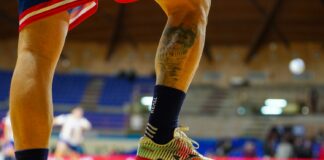 Player with foot on a soccer ball indoors.
