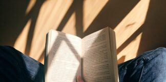 person holding book sitting on brown surface