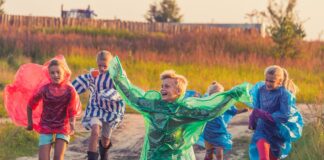 boy in green jacket and red shirt running on road during daytime
