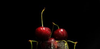 a glass filled with cherries sitting on top of a table