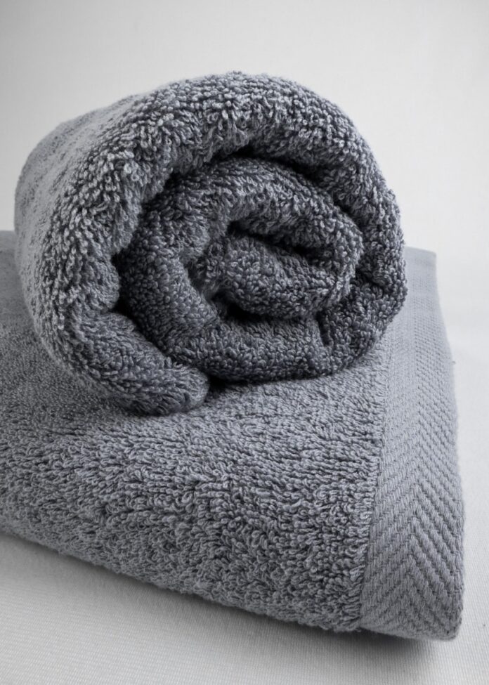 Photo by MADEINEGYPT.CA a gray towel folded on top of a bed