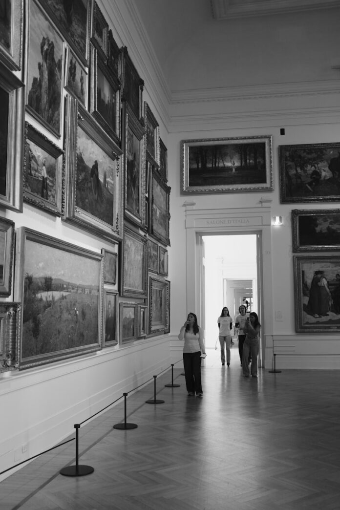 People walking through a gallery of framed paintings.