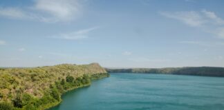green and brown mountain beside body of water under blue sky during daytime