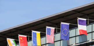 Flags of various nations fly on building.