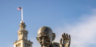 Bronze statue of mahatma gandhi holding a staff.