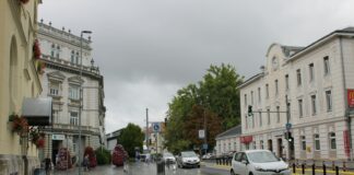 Cars drive down a street on a cloudy day.