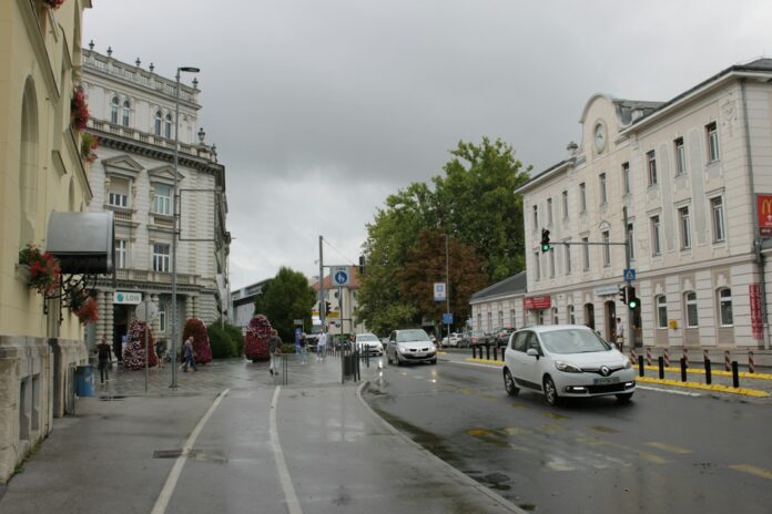 Cars drive down a street on a cloudy day.