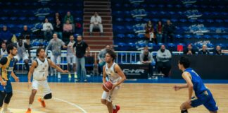 Basketball players competing on a wooden court