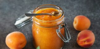 a jar of peach jam next to some peaches