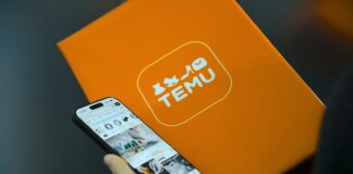 Person holding phone with temu logo box