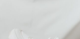 a person holding onto a white tennis shoe