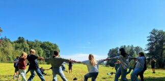 Children playing tug-of-war in a grassy field.
