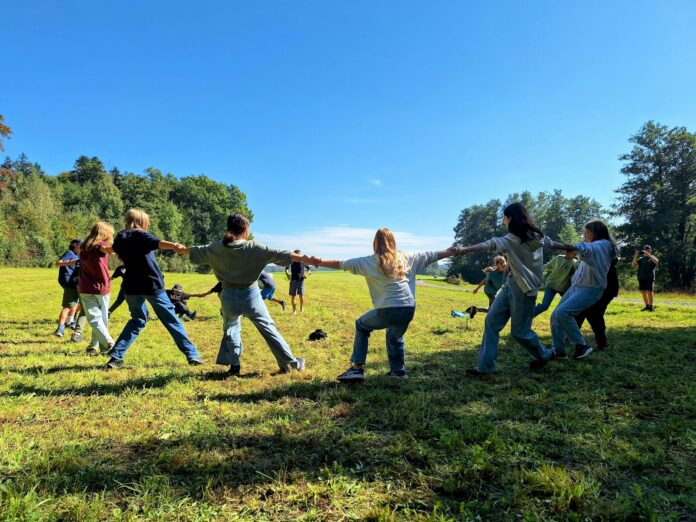 Children playing tug-of-war in a grassy field.