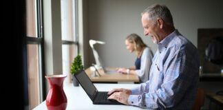 man in blue and white plaid dress shirt using black laptop computer