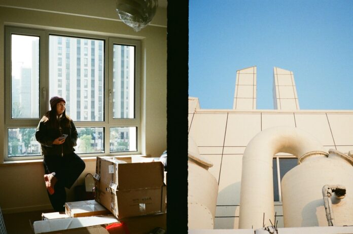 Person by window with boxes, industrial building exterior.